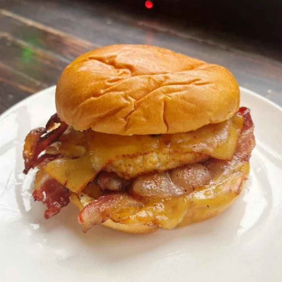 Olivier Cafe's breakfast sandwich with bacon, egg, and melted cheese on a brioche bun.